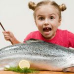Criança comendo peixe