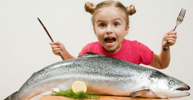 Criança comendo peixe