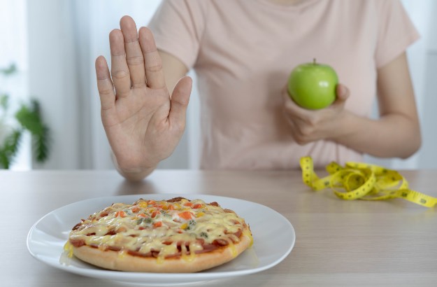 Dieta e perda de peso, a mulher rejeita comer pizza e escolher comer maça verde para uma boa saude e forma esbelta